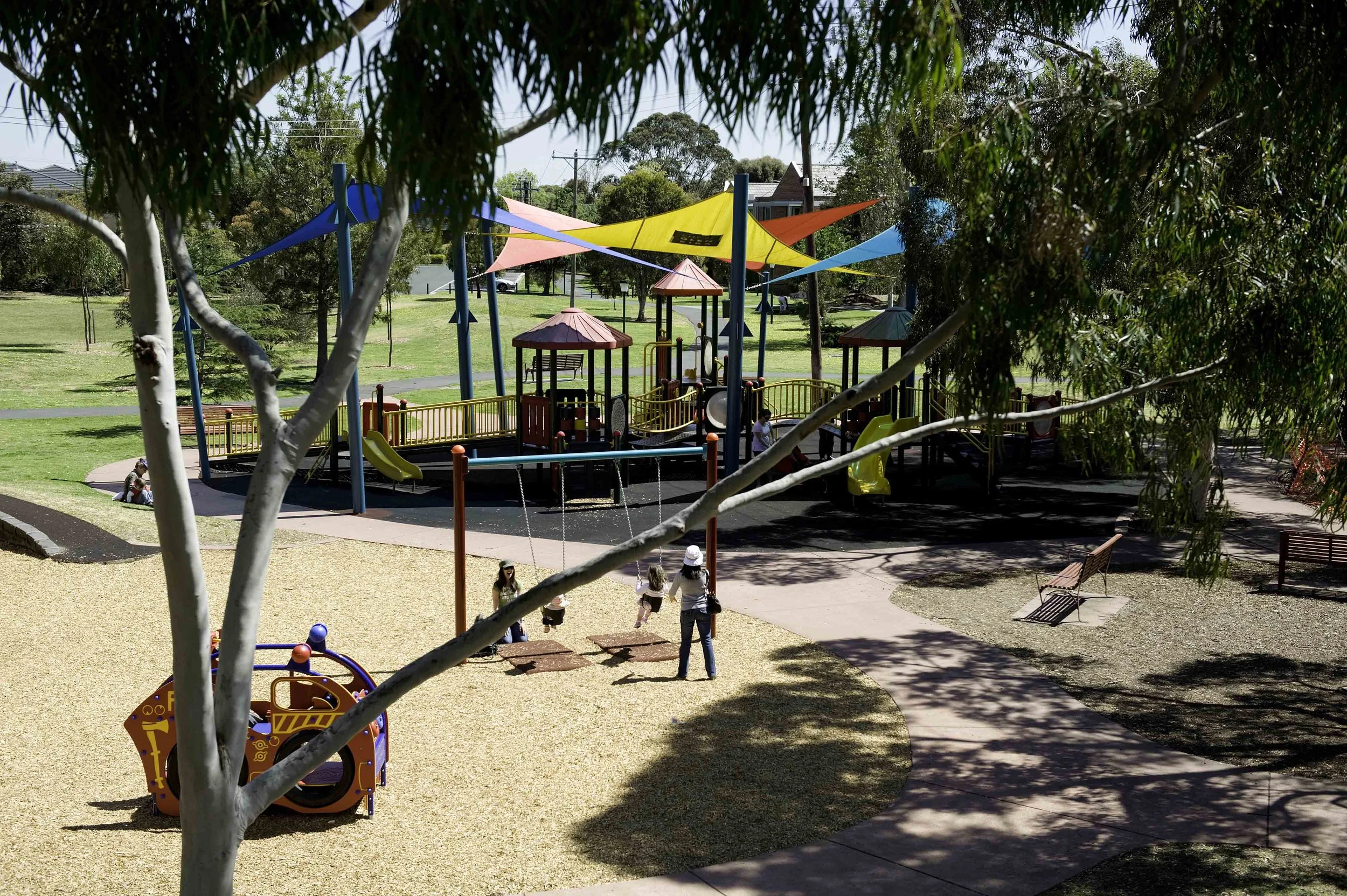 Children playing on swings and slides at a colorful playground in a park.