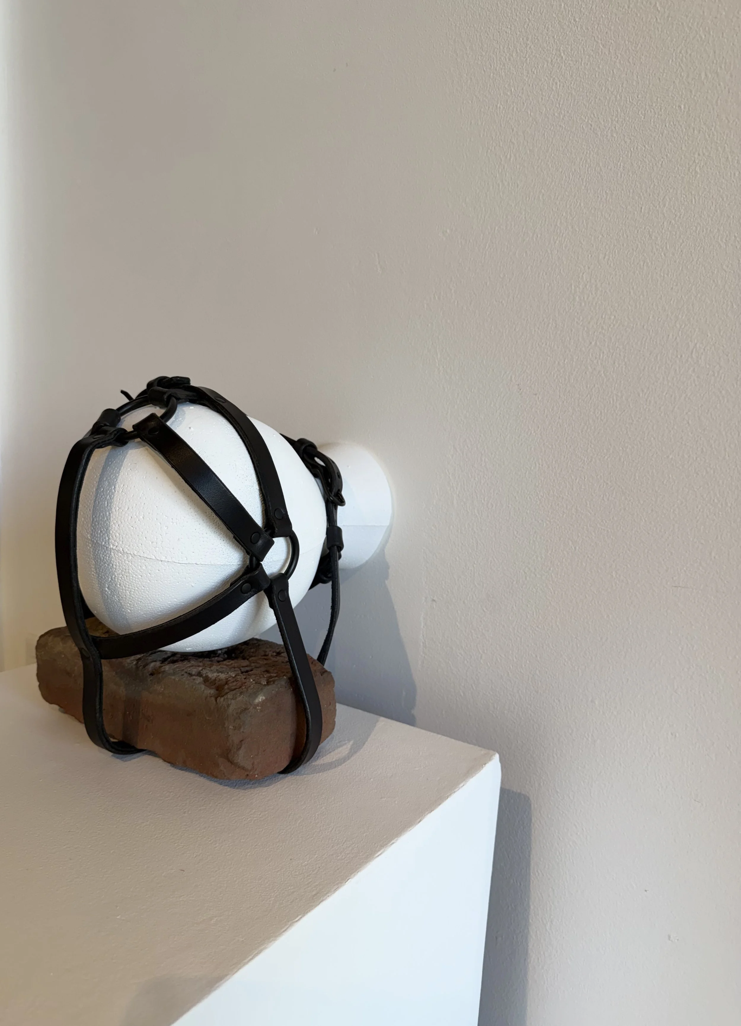 Catherine Menard. Bricked Up . 2026. Found object, rivets, leather, nails. 10 x 10 x 6 inches.