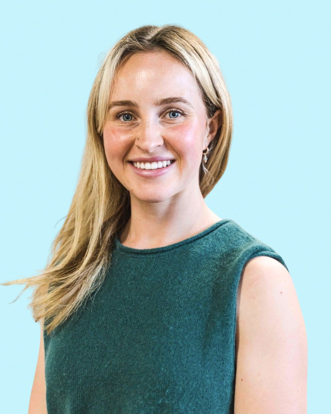 Portrait of a smiling woman with blonde hair, wearing a sleeveless teal top against a light blue background.