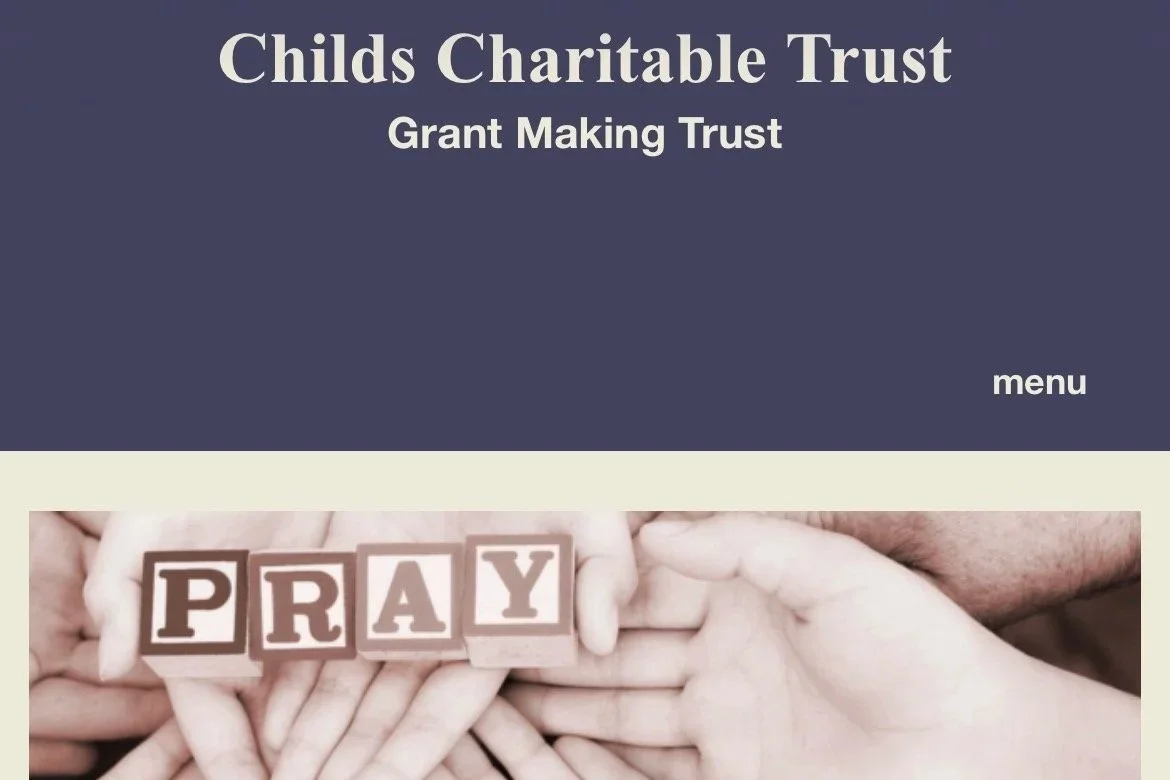 The webpage header reads 'Childs Charitable Trust Grant Making Trust' with a menu option. Below, there is a photo of multiple hands holding wooden blocks spelling out 'PRAY'.