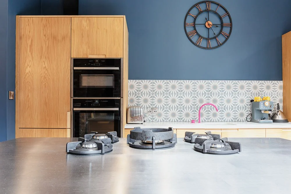 Image of kitchen with hob and pink tap, with patterned tiles
