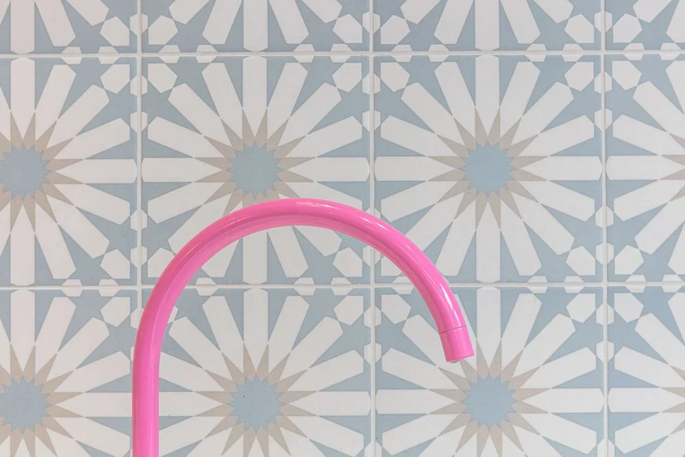 Close up of pink tap against patterned tiles, kitchen interior design, Manchester