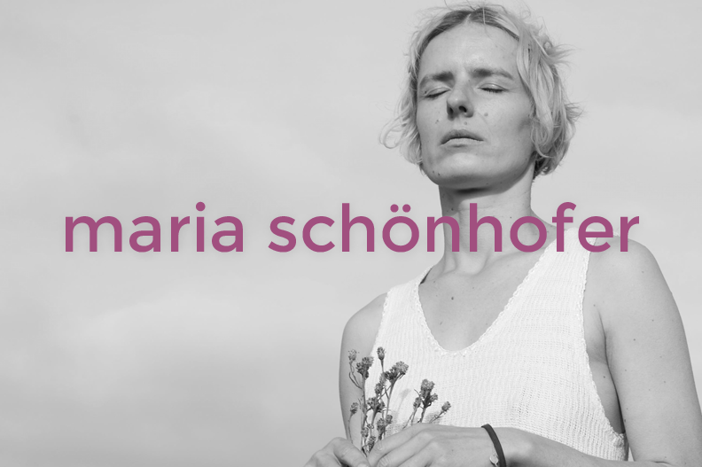 Black and white photo of a woman with short, wavy hair, wearing a sleeveless white top, holding flowers, with her eyes closed and a serene expression.