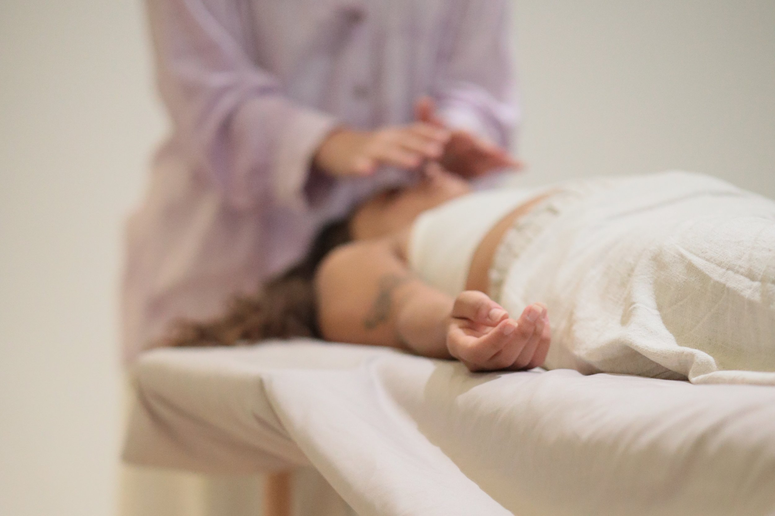 A person receiving a massage on their back in a spa setting, with the focus on their hand resting on the massage table.