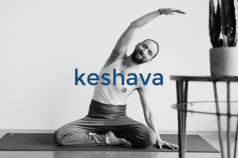 Man practicing yoga in a seated twist pose indoors, with the word 'keshava' overlaid in blue text.