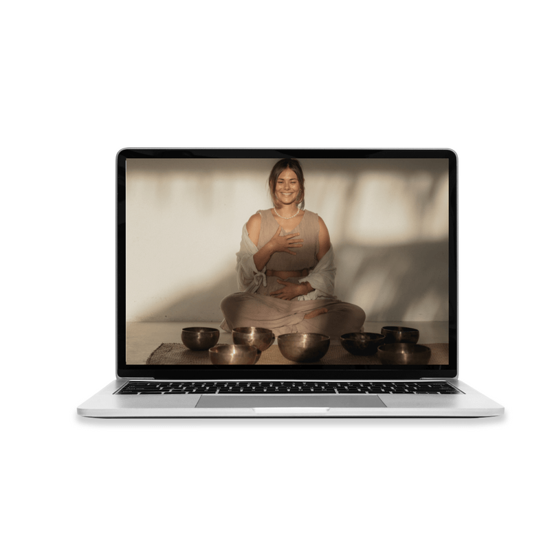 Laptop displaying a woman sitting cross-legged, smiling, and touching her chest with one hand, surrounded by six singing bowls on a mat.