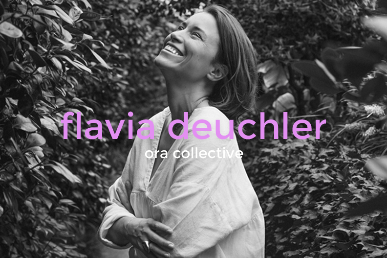 Black and white photo of a woman smiling and looking up, standing outdoors among leafy bushes, with the text 'flavia deuchler' and 'ora collective' overlaid in purple and white.