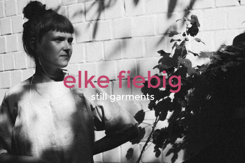 Black and white photo of a woman with dark hair in an updo, standing next to a brick wall and plant, with text overlay reading "elke fiebig" and "still garments".