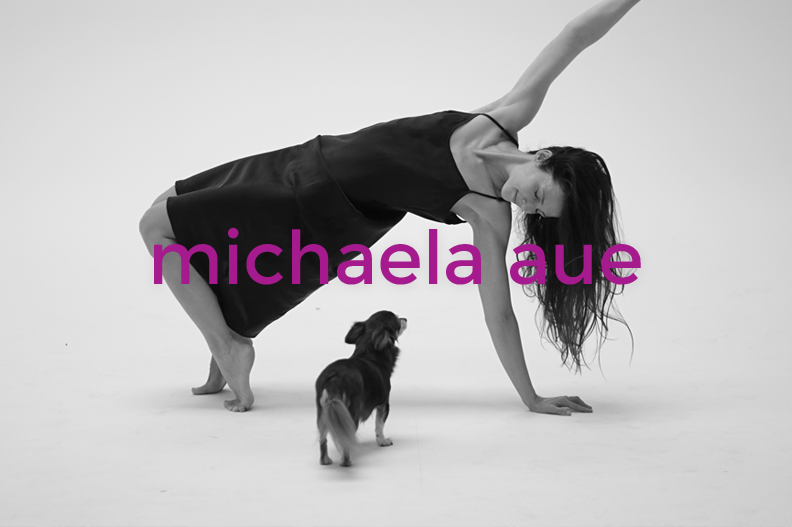 Woman in a black dress performing a yoga pose with a small dog watching, set against a plain background with the name 'michaela avenue' written in purple across the image.