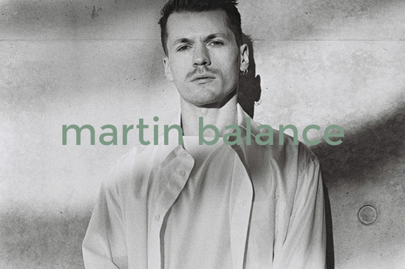Black and white portrait of a man with a serious expression, wearing a button-up shirt, with the text 'martin balance' overlaid.