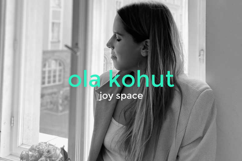 Black and white photo of a woman with long hair, sitting by a window with her eyes closed, smiling softly. Text overlay reads 'ola kohut joy space' in teal and white.