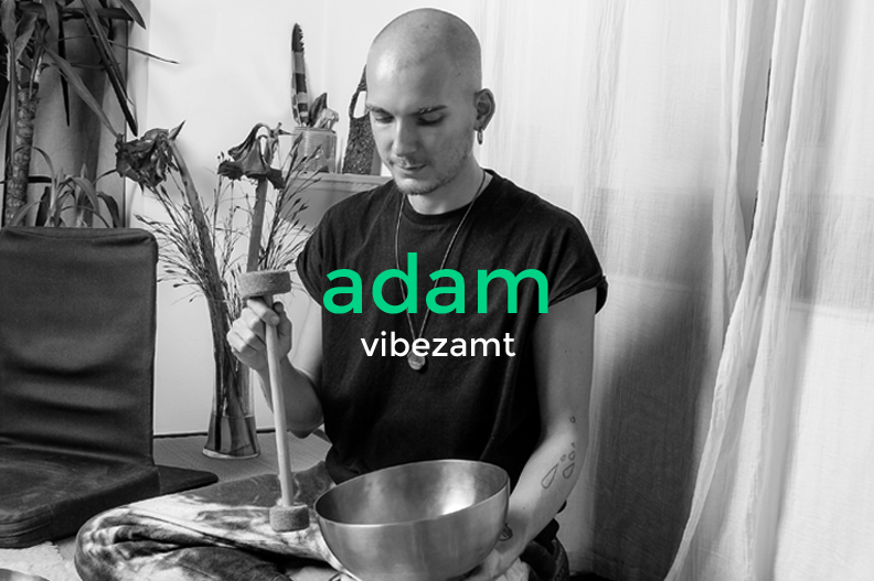 A person with a shaved head and tattoos wearing a black t-shirt, sitting in a room with plants and curtains, holding a bowl and a mallet, with the text 'adam vibezamt' overlaid.
