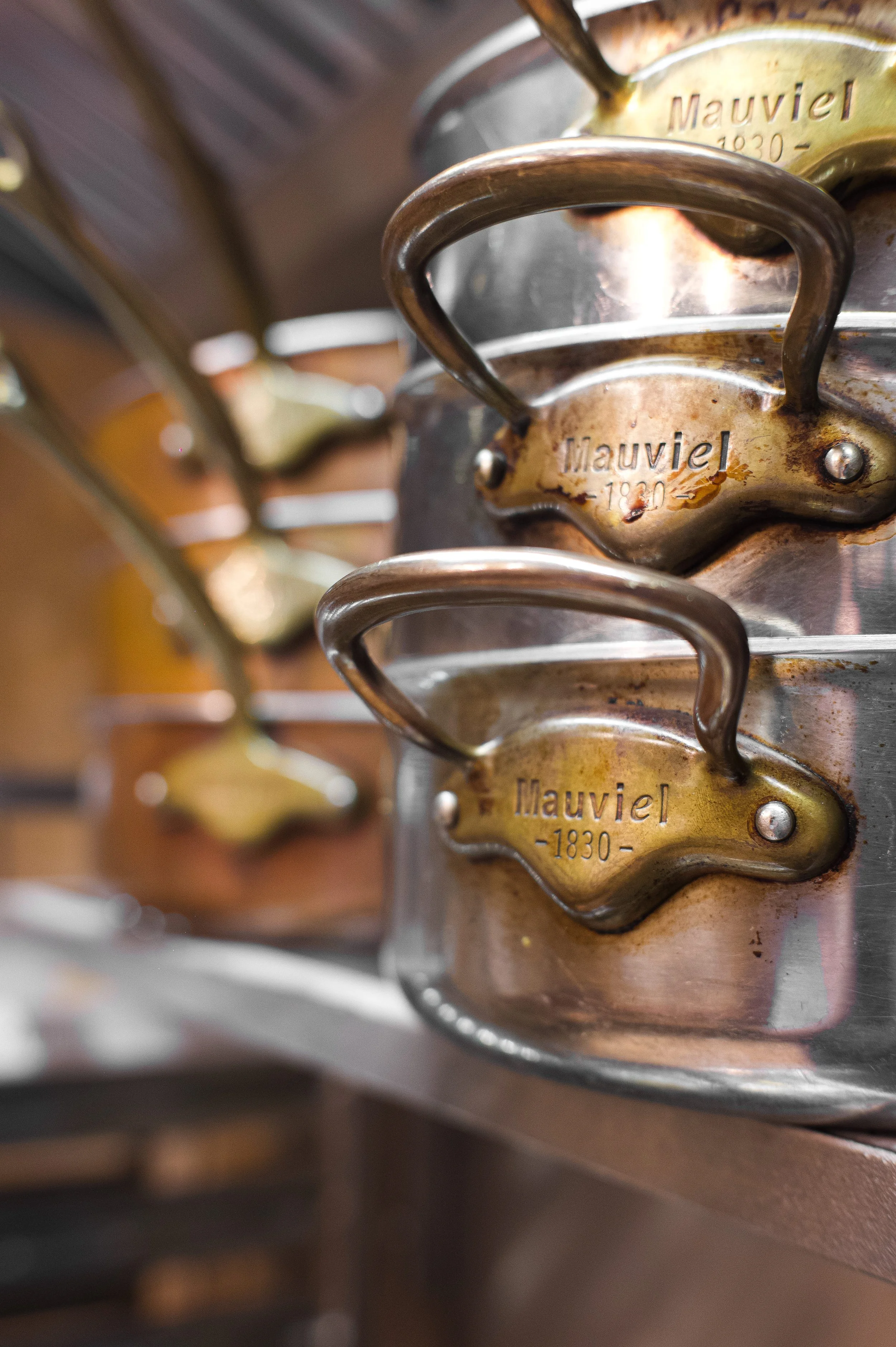 Antique 'Mauviel' engraved copper mold stored vertically, used for cooking, with a stainless steel surface in the background.