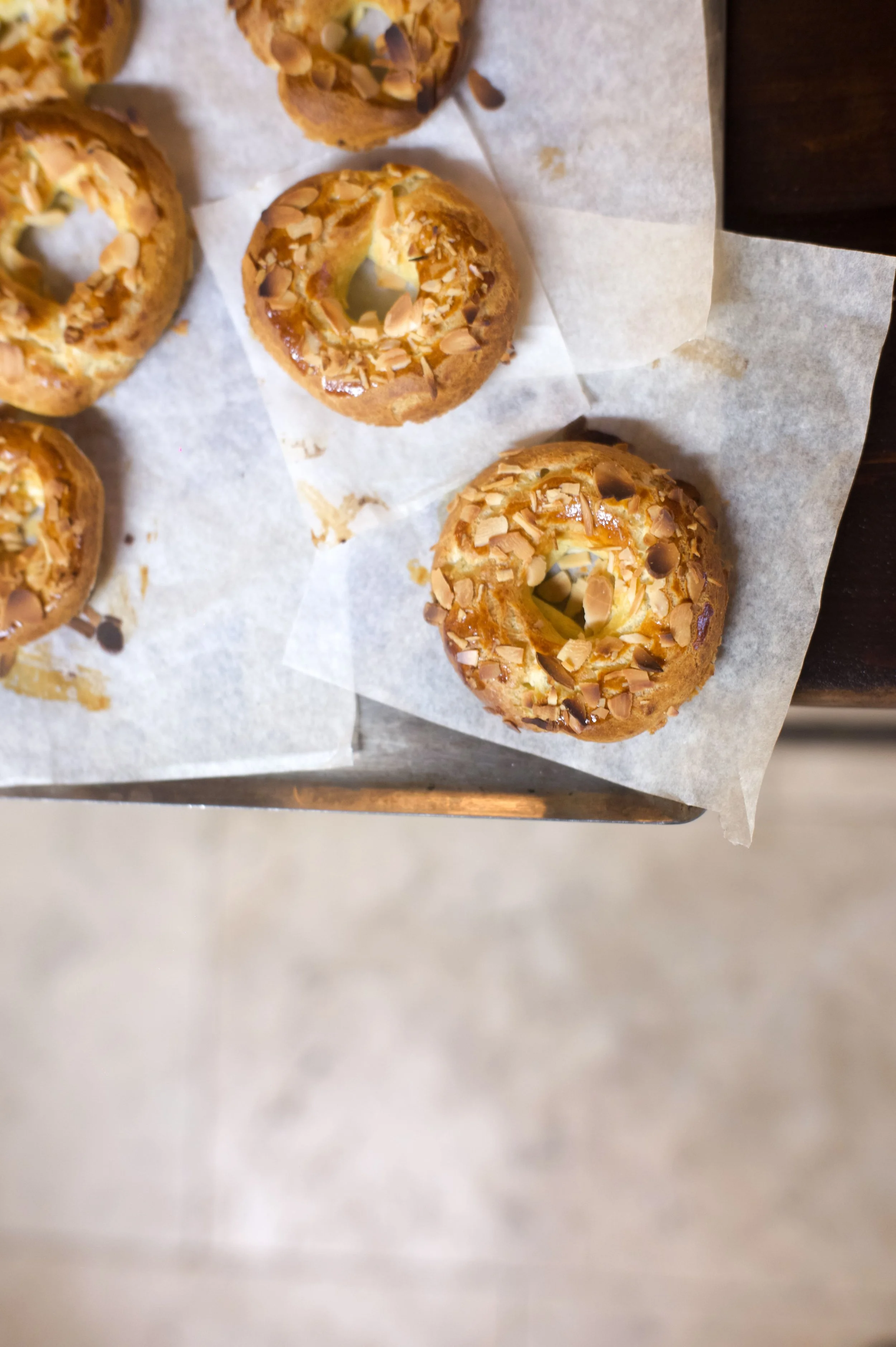 Petits gâteaux ronds, garnis d'amandes effilées et de chocolat, posés sur du papier sulfurisé