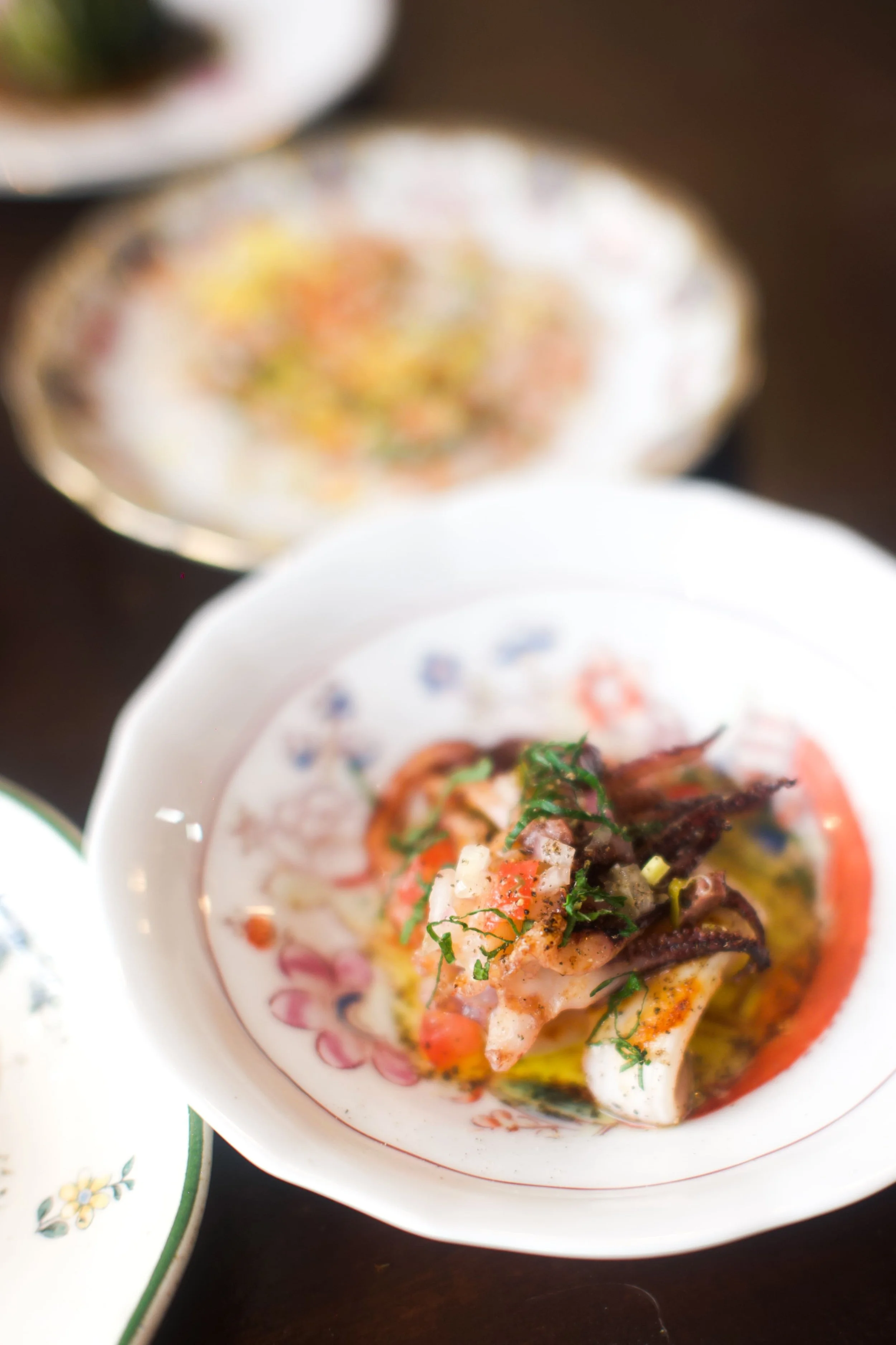 Une assiette de fruits de mer avec des herbes et de l'huile, entourée de plusieurs autres plats évaporés.