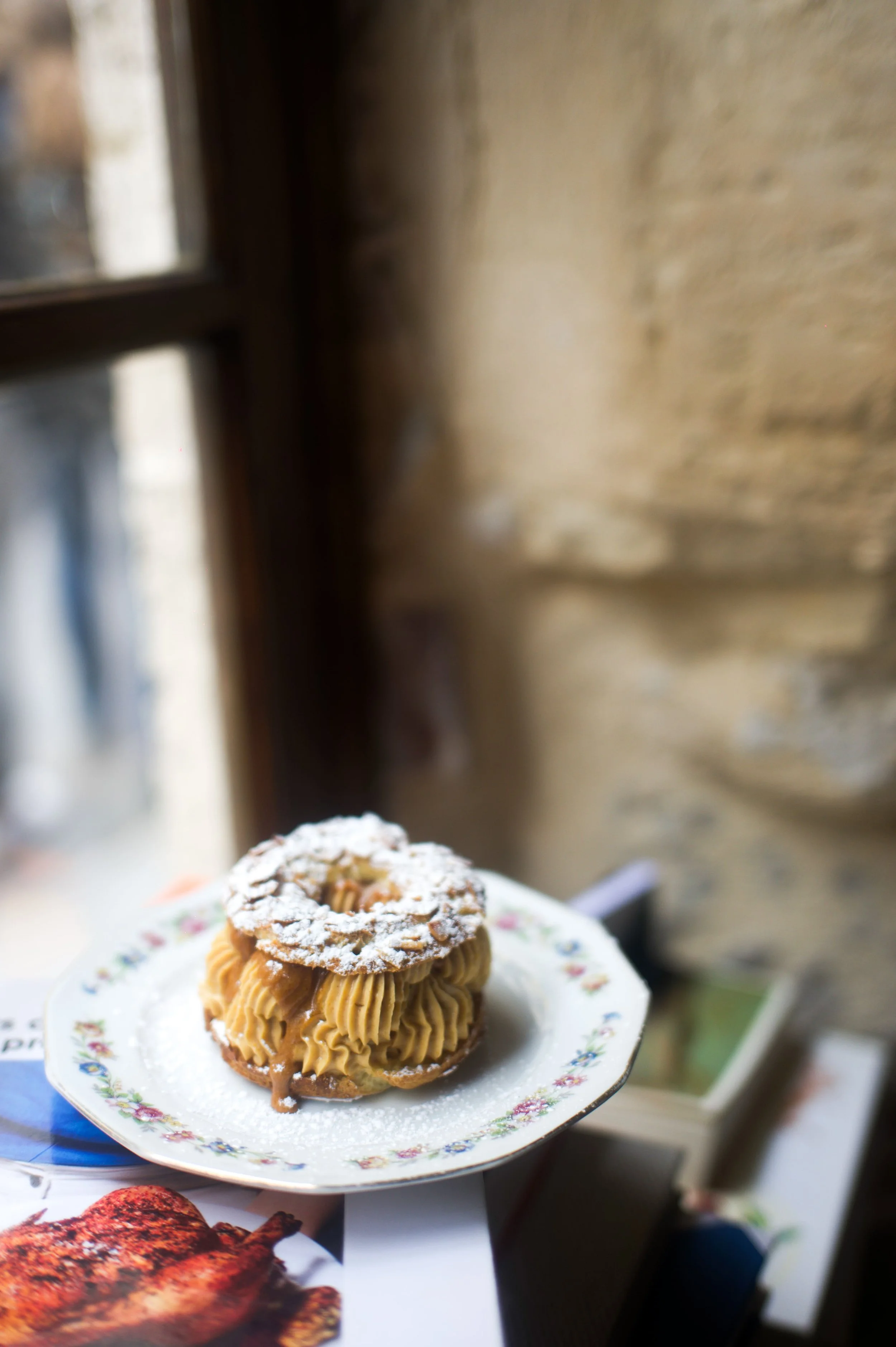 Dessert avec une pâte à choux et une garniture crème, saupoudré de sucre glace, présenté sur une assiette florale