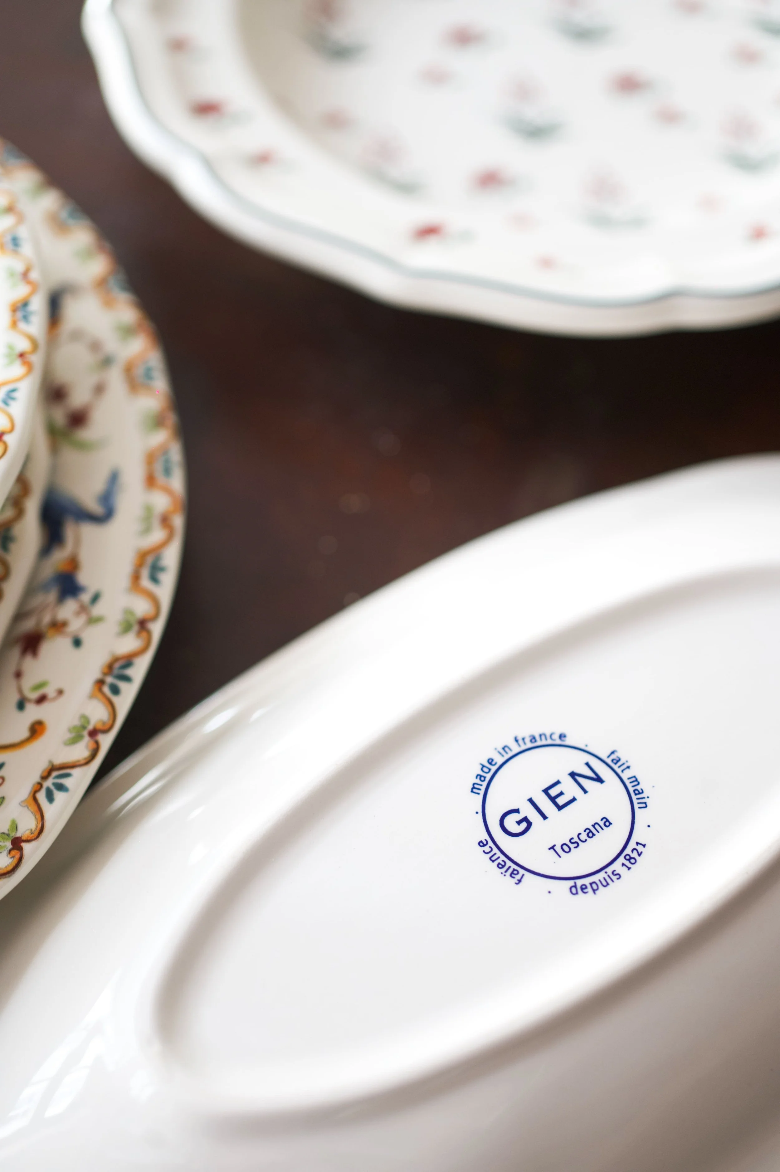Assiettes en porcelaine blanche avec des motifs colorés, marquée au dos avec le logo 'GIEN' et des inscriptions en français, indiquant qu'elles sont fabriquées en France, dans la région Toscane, depuis 1821.