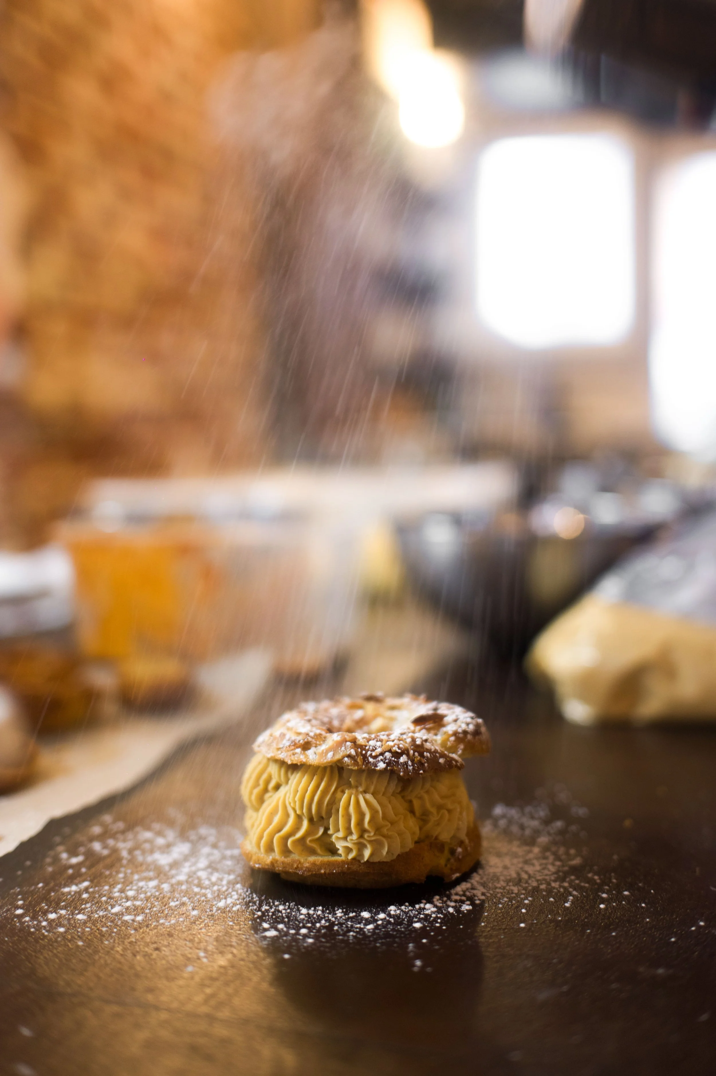 Dessert au caramel avec une garniture de poudre blanche, probablement de la poudre de sucre glace, sur une surface noire.