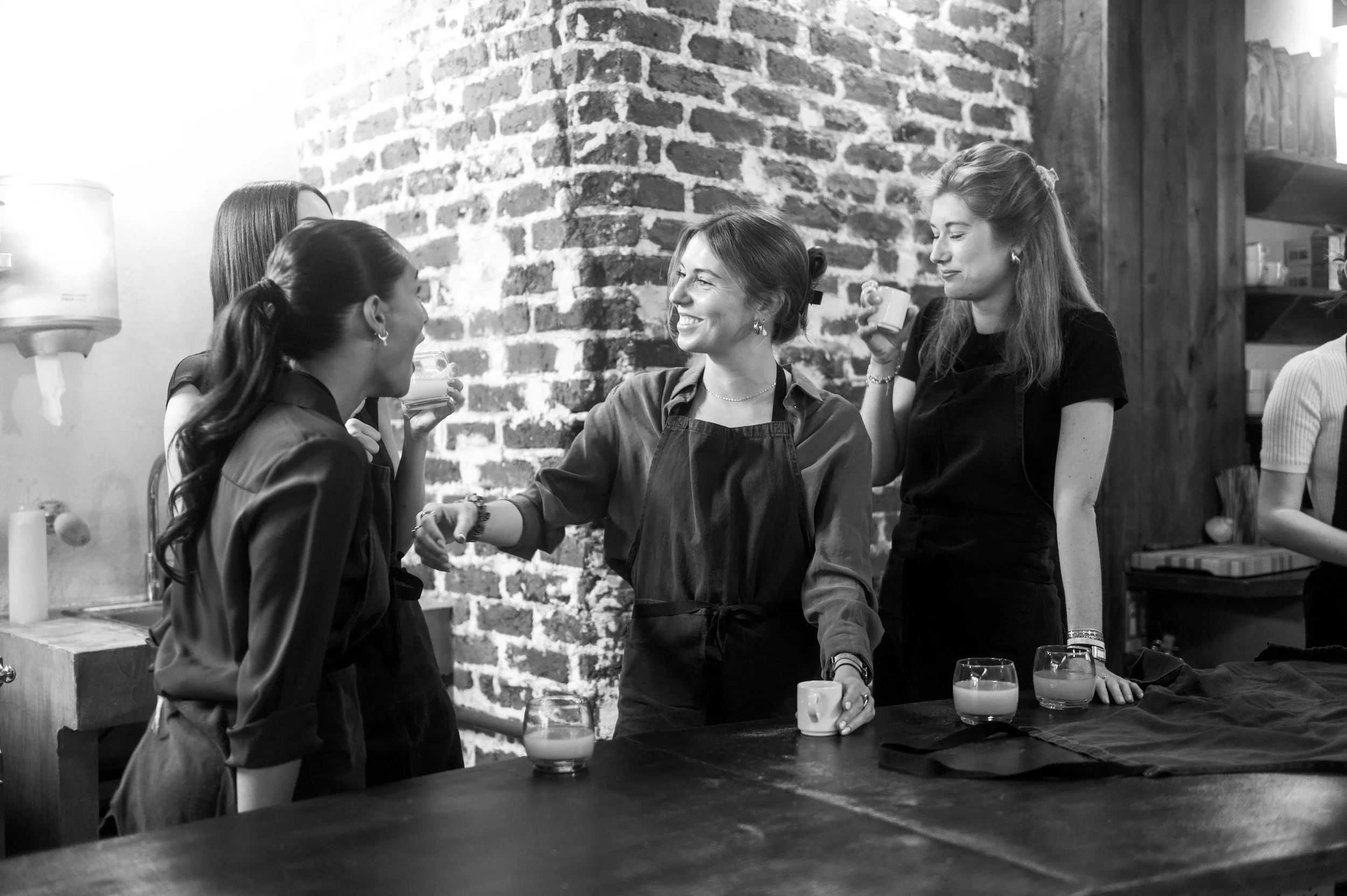 Groupe de femmes partageant un moment convivial dans une cuisine, en noir et blanc.