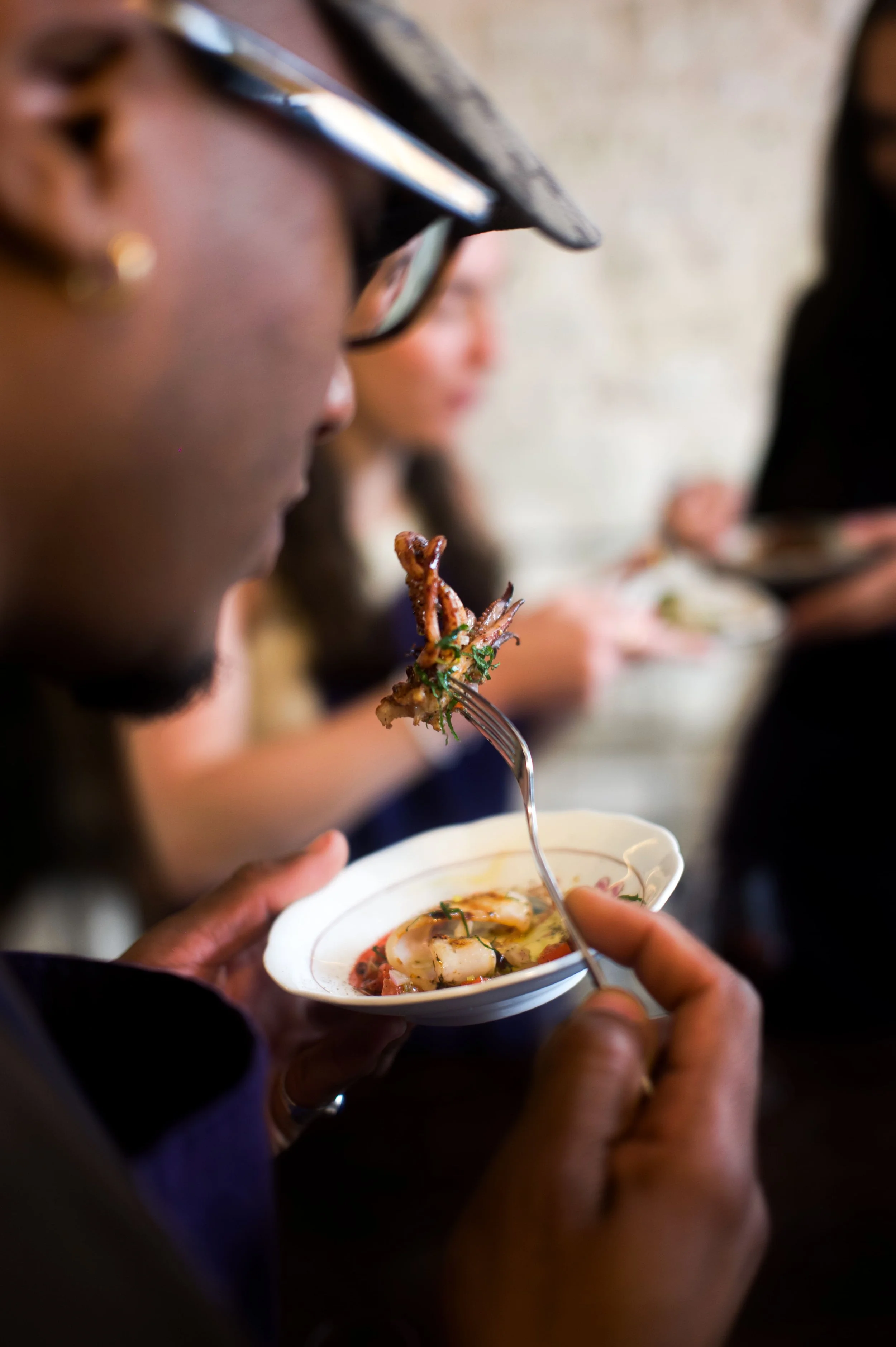 Personne dégustant un plat de fruits de mer, notamment des calamars et des crevettes, dans un restaurant.