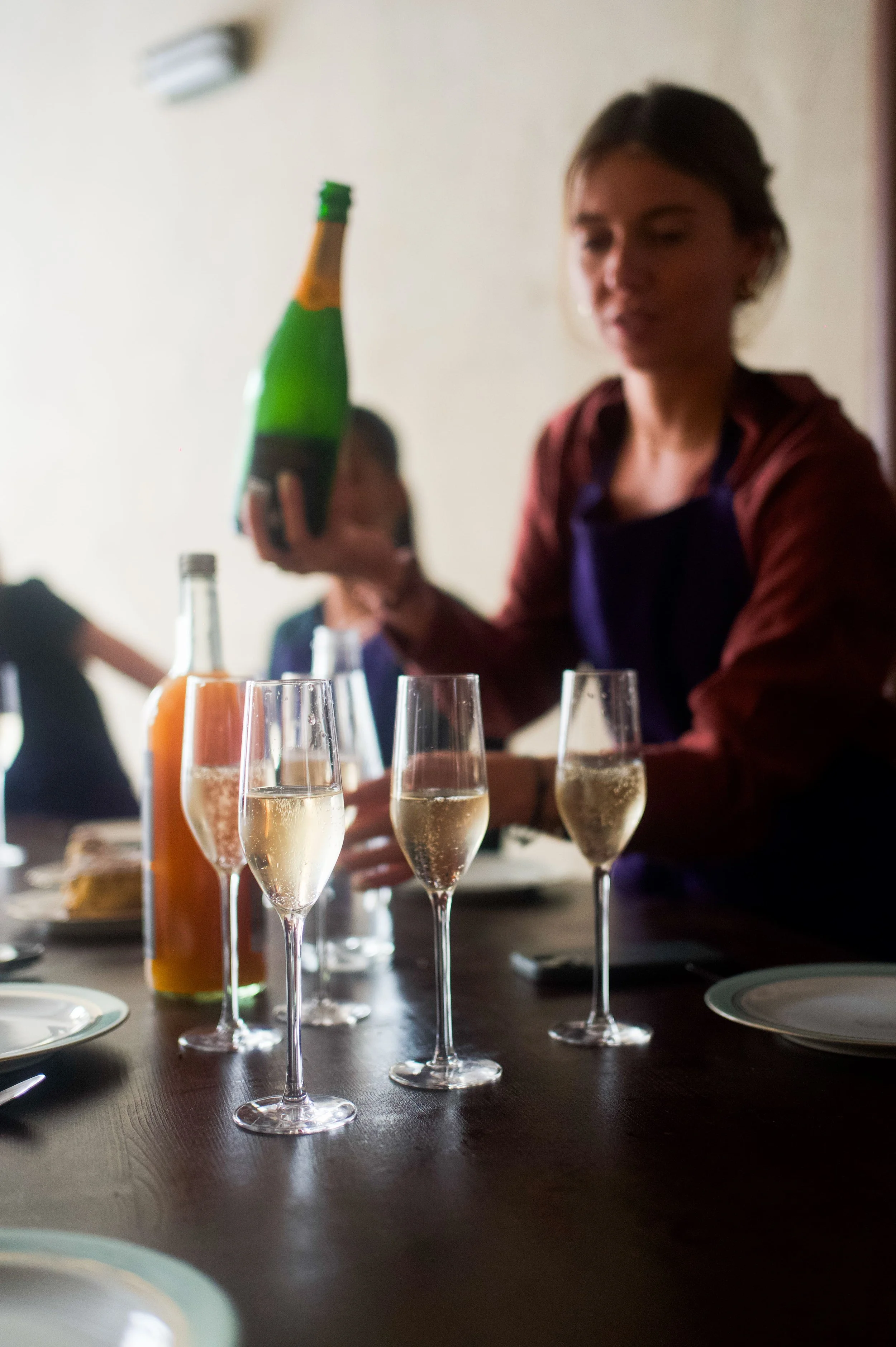Une femme serve du champagne lors d'une fête ou d'une célébration, avec plusieurs flûtes de champagne sur la table