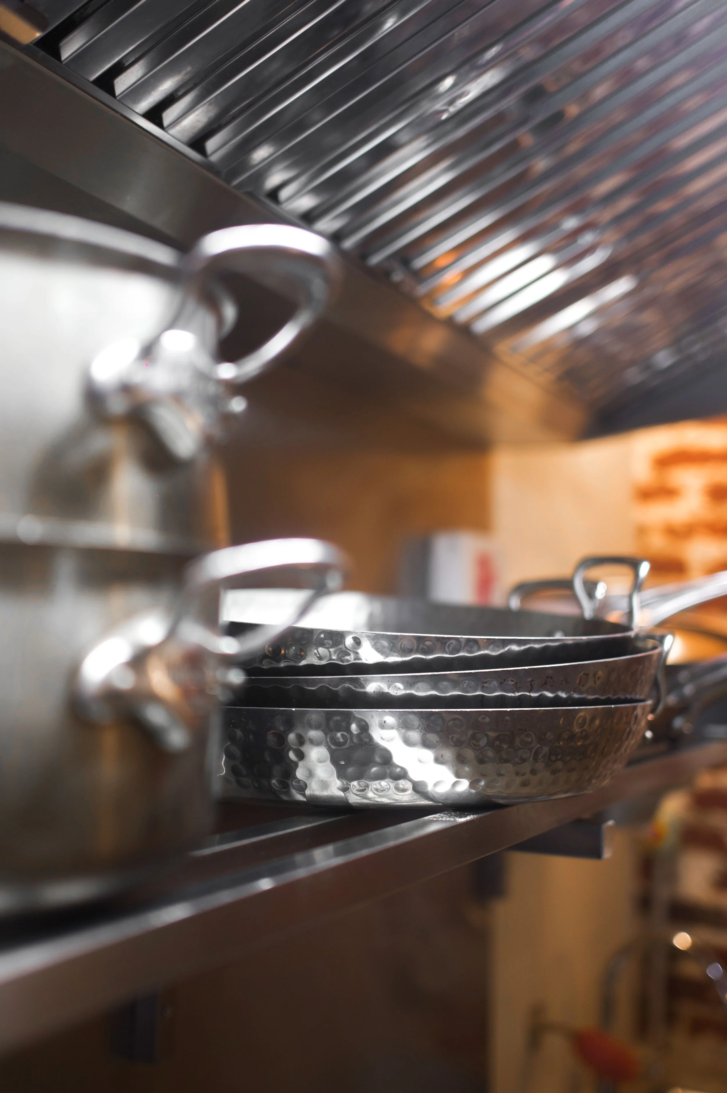 Poêles en acier inoxydable empilées sur une étagère en cuisine.