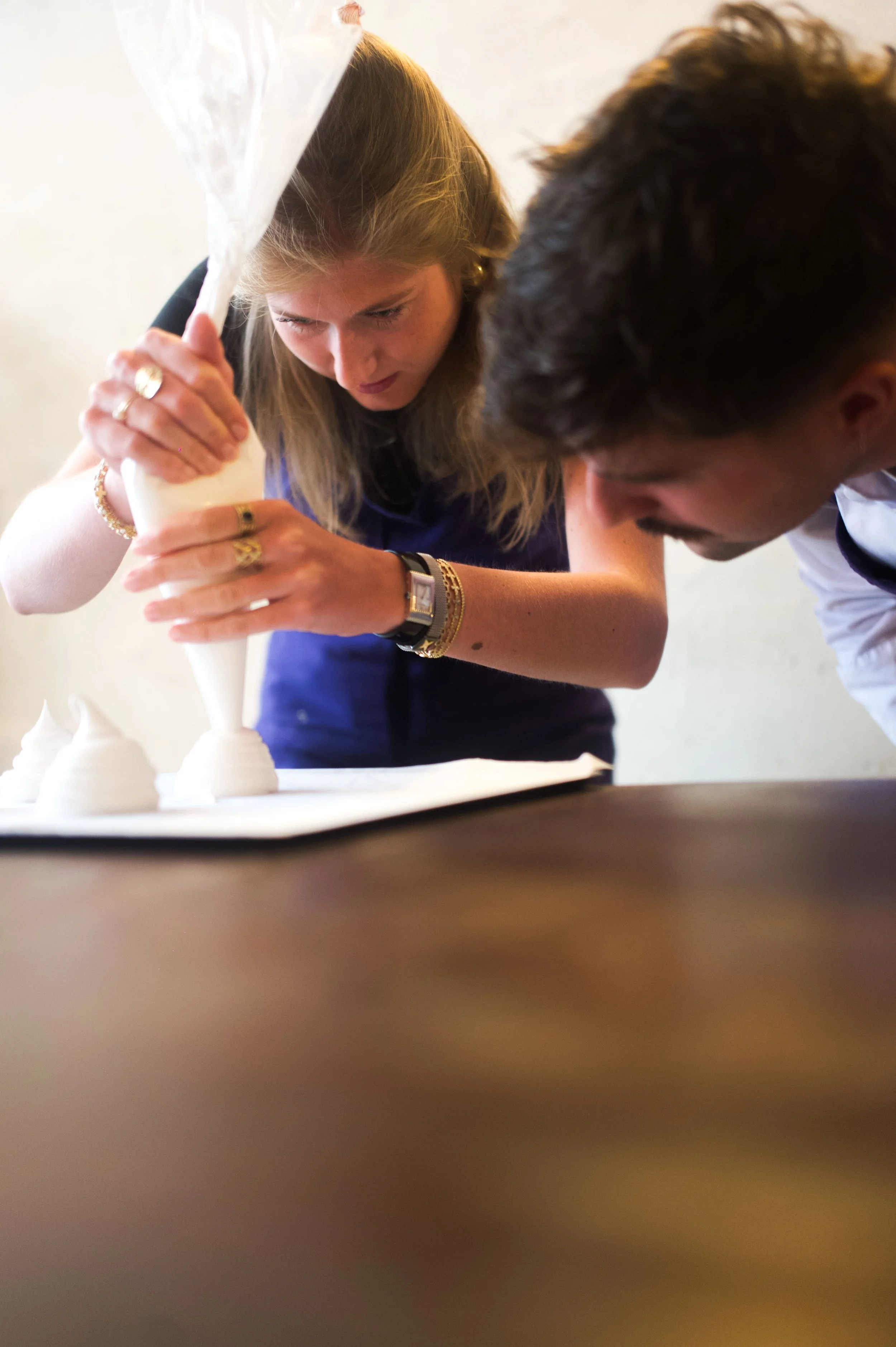 Une femme et un homme décorent un gâteau avec de la crème pour une celebration.