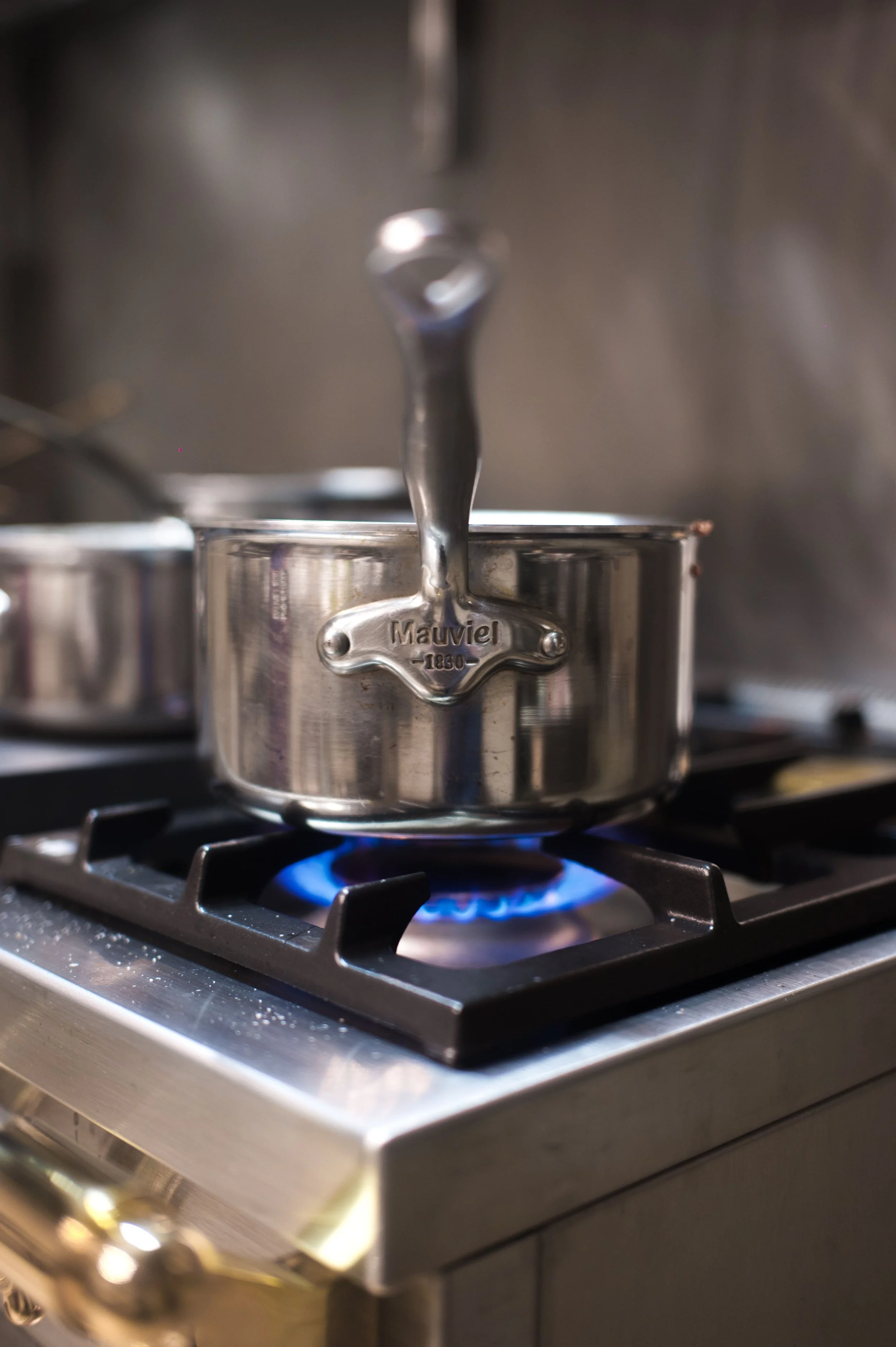 Une casserole en acier inoxydable sur une cuisinière à gaz allumée.