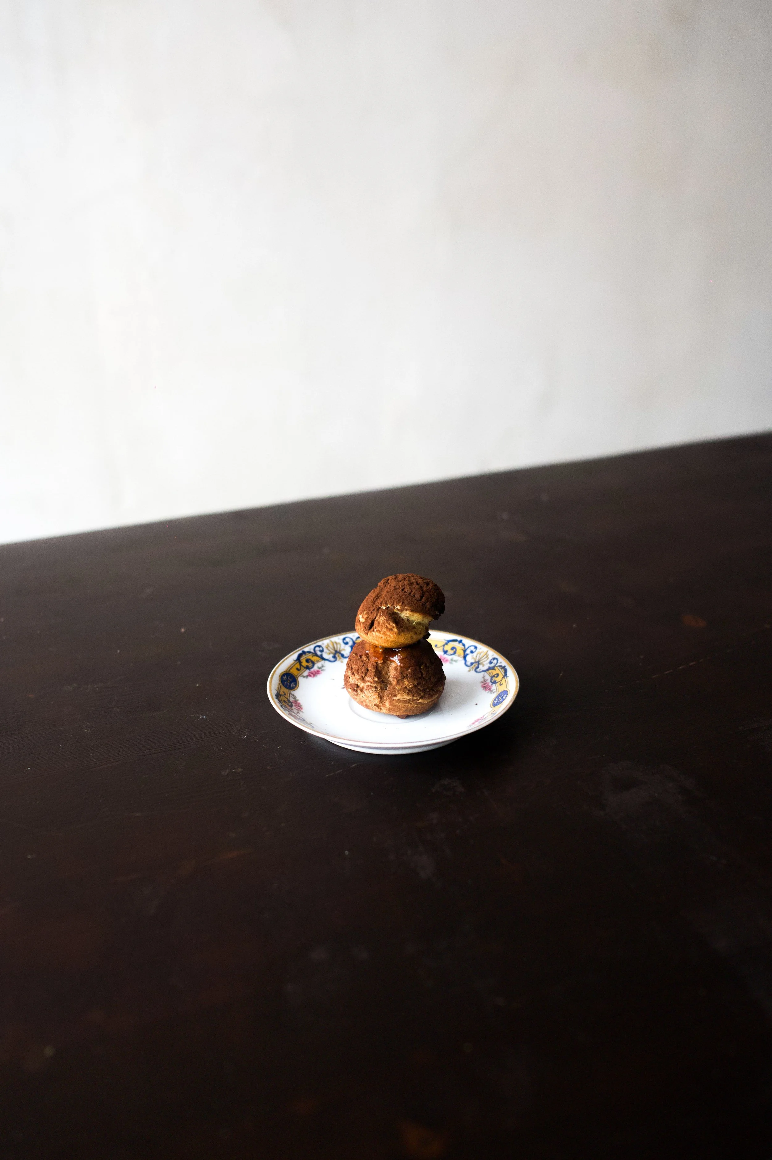 Deux cookies sur une petite assiette avec décoration. La surface est sombre, avec un mur blanc en arrière-plan.