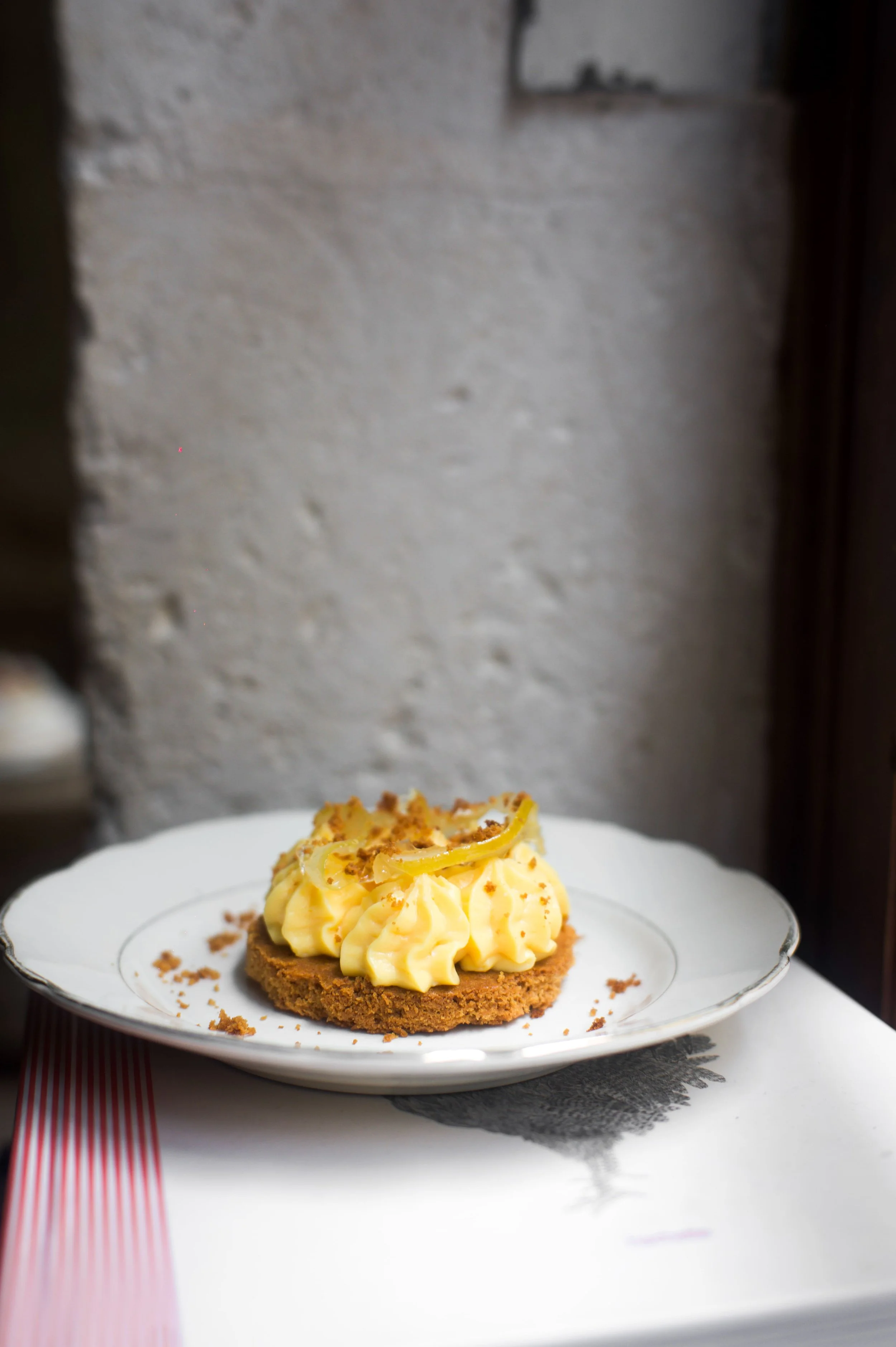 Gâteau avec une couche de crème à la citron, décoré avec des tranches de citron confit et des miettes."}