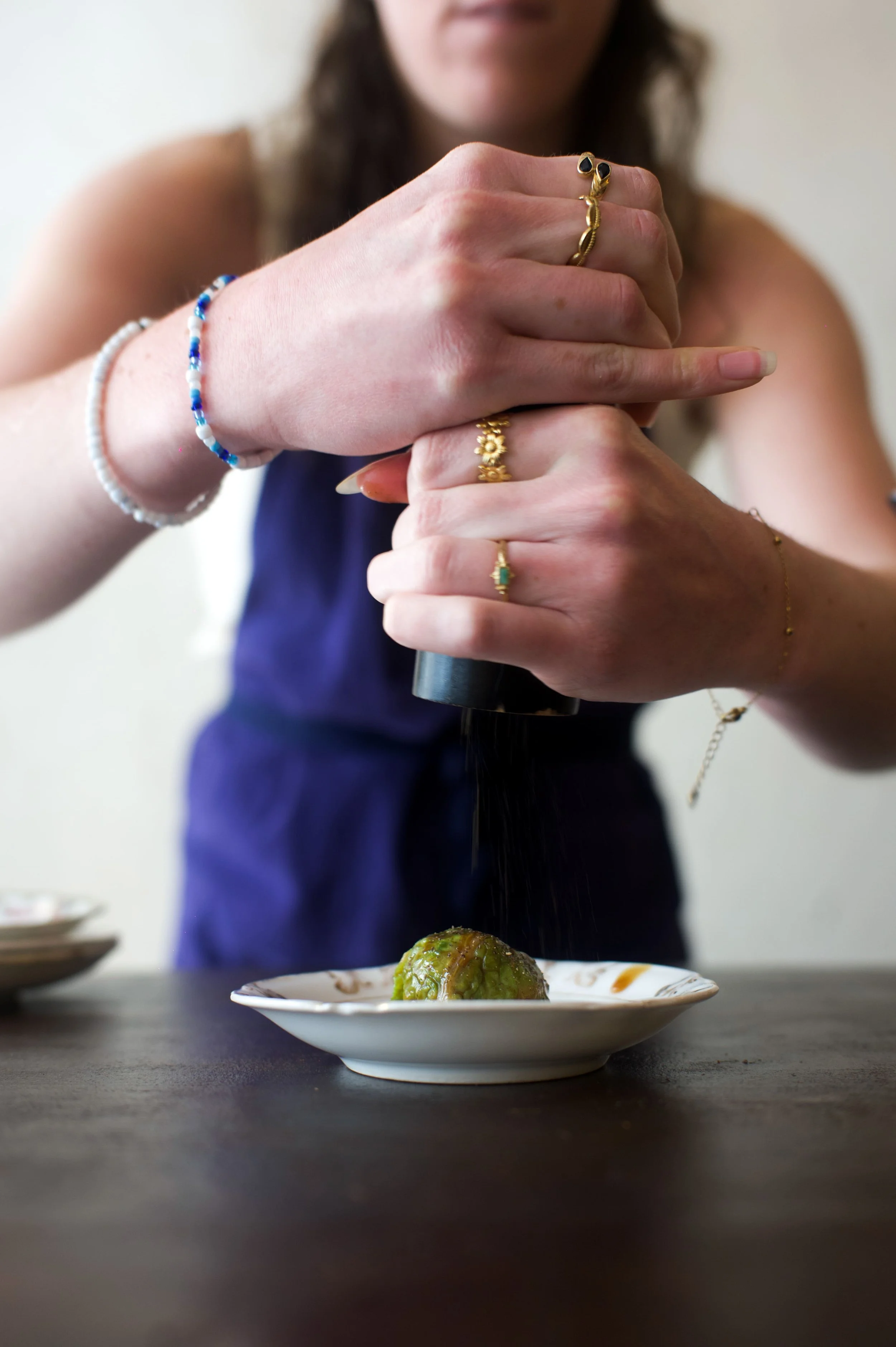 Une femme râpant une aubergine sur une petite assiette blanche.