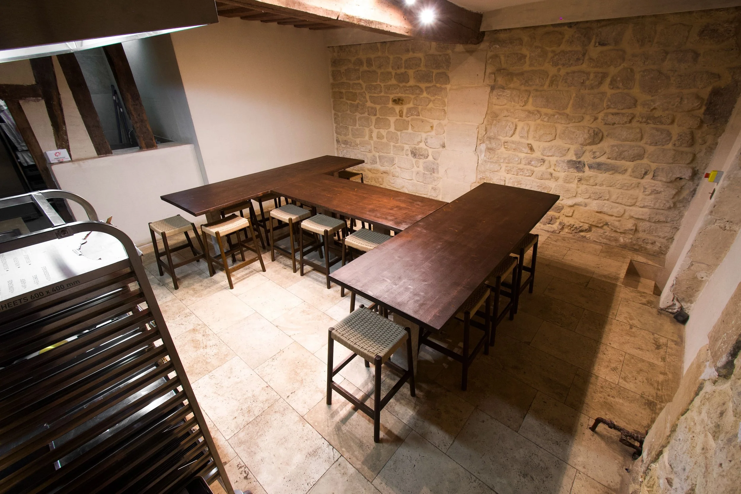 Meeting room with large wooden table and wooden chairs with fabric seats, stone walls.