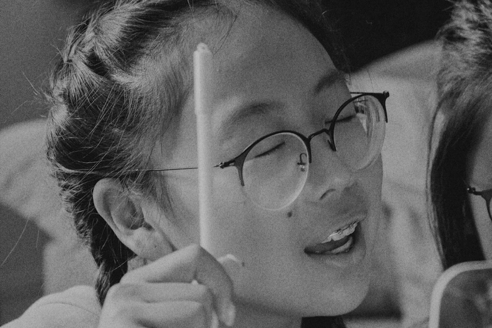 An asian girl with glasses raising a hand to give an opinion during a body image workshop a school
