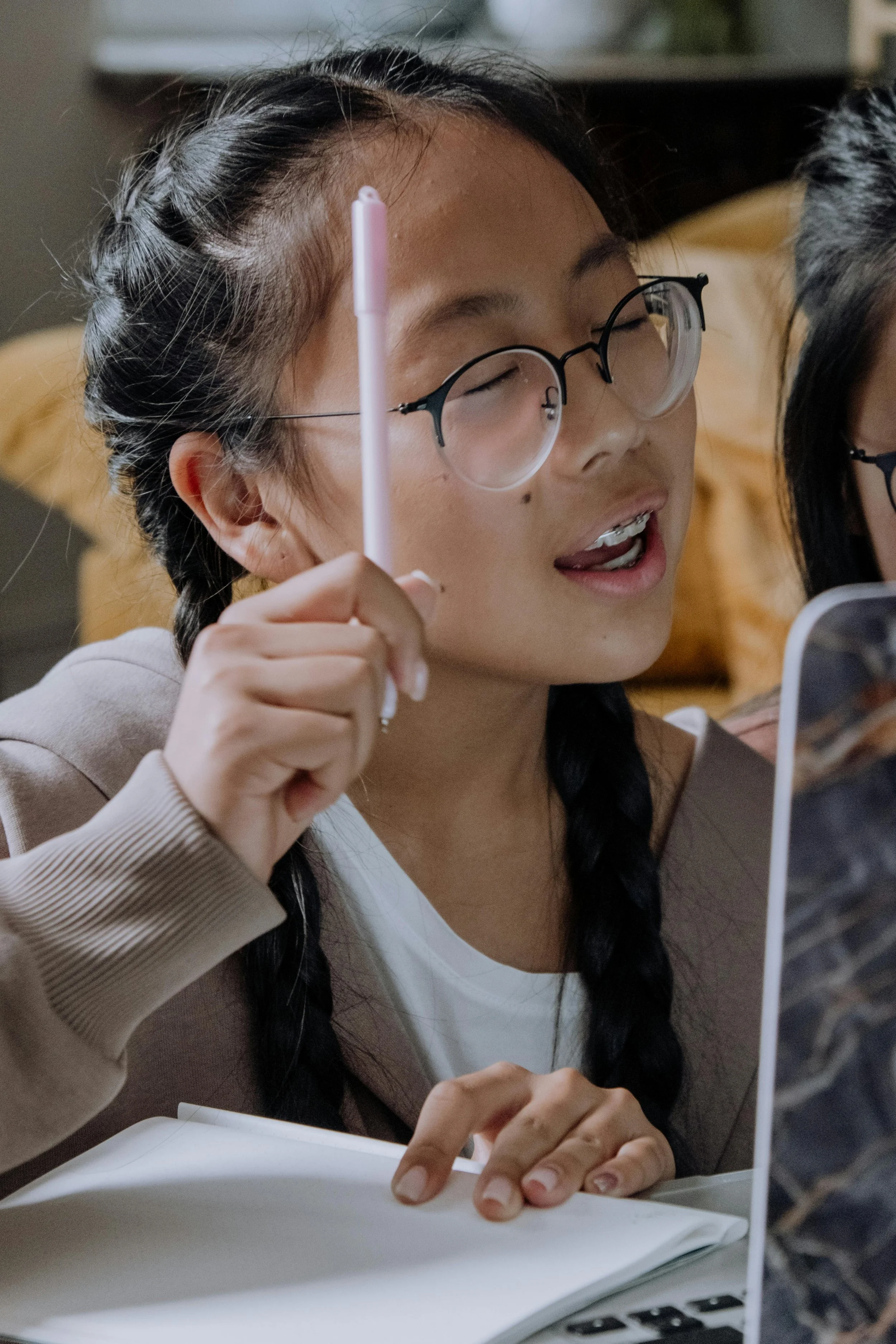 An Asian girl raising her hand in the classroom during a body image lesson at school