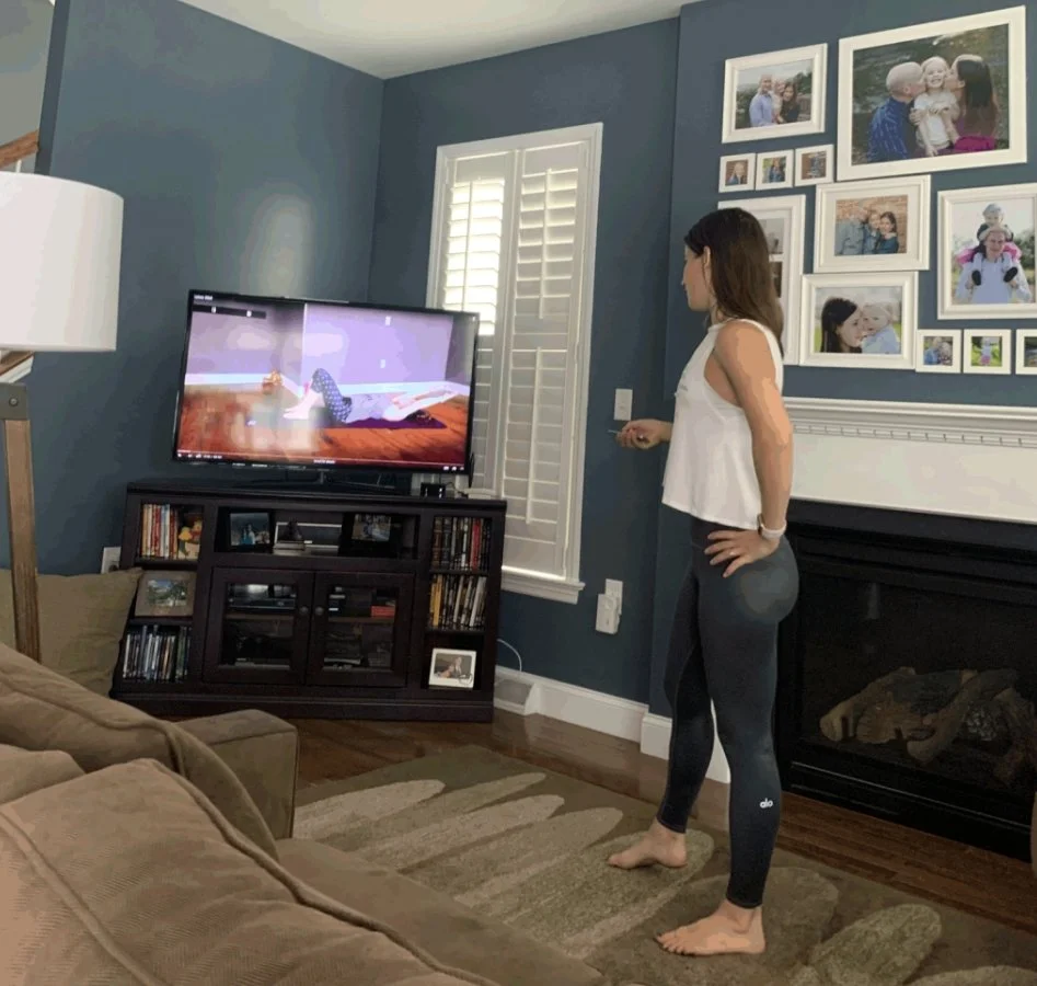 A woman stands in front of a cozy fireplace in a stylish living room, creating a warm and inviting atmosphere.