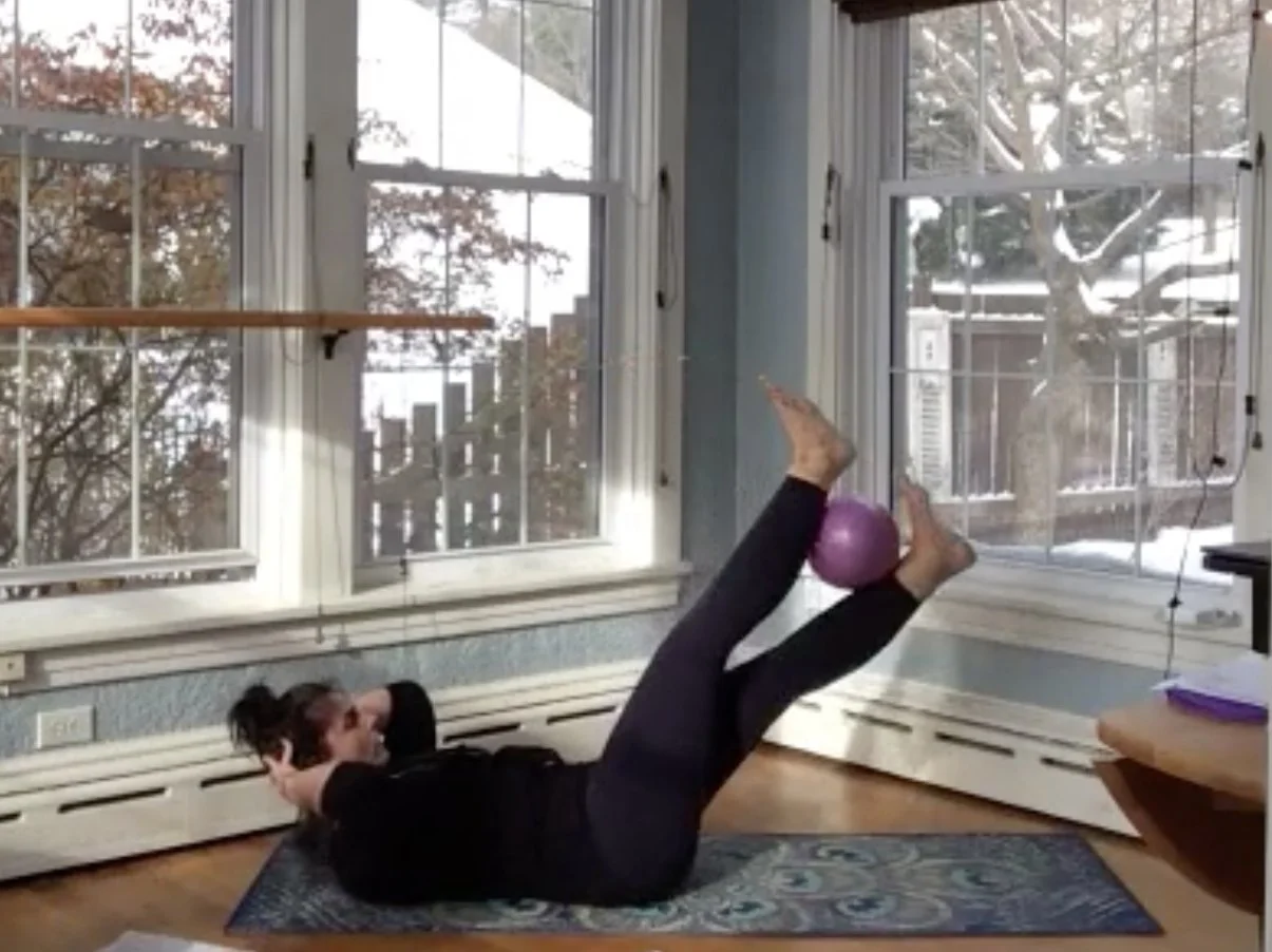 A woman practicing yoga in a serene pose in front of a large window, allowing natural light to fill the space.