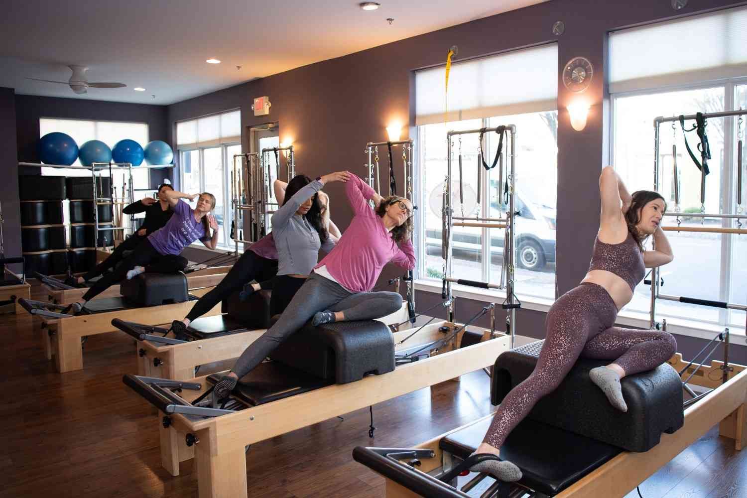 A woman engages in a pilates session on a reformer, demonstrating strength and control in her movements.