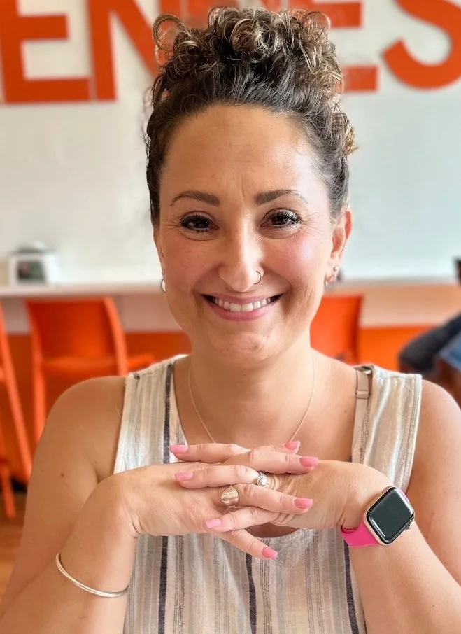 A woman shows her wrist adorned with a watch and pink-painted nails.