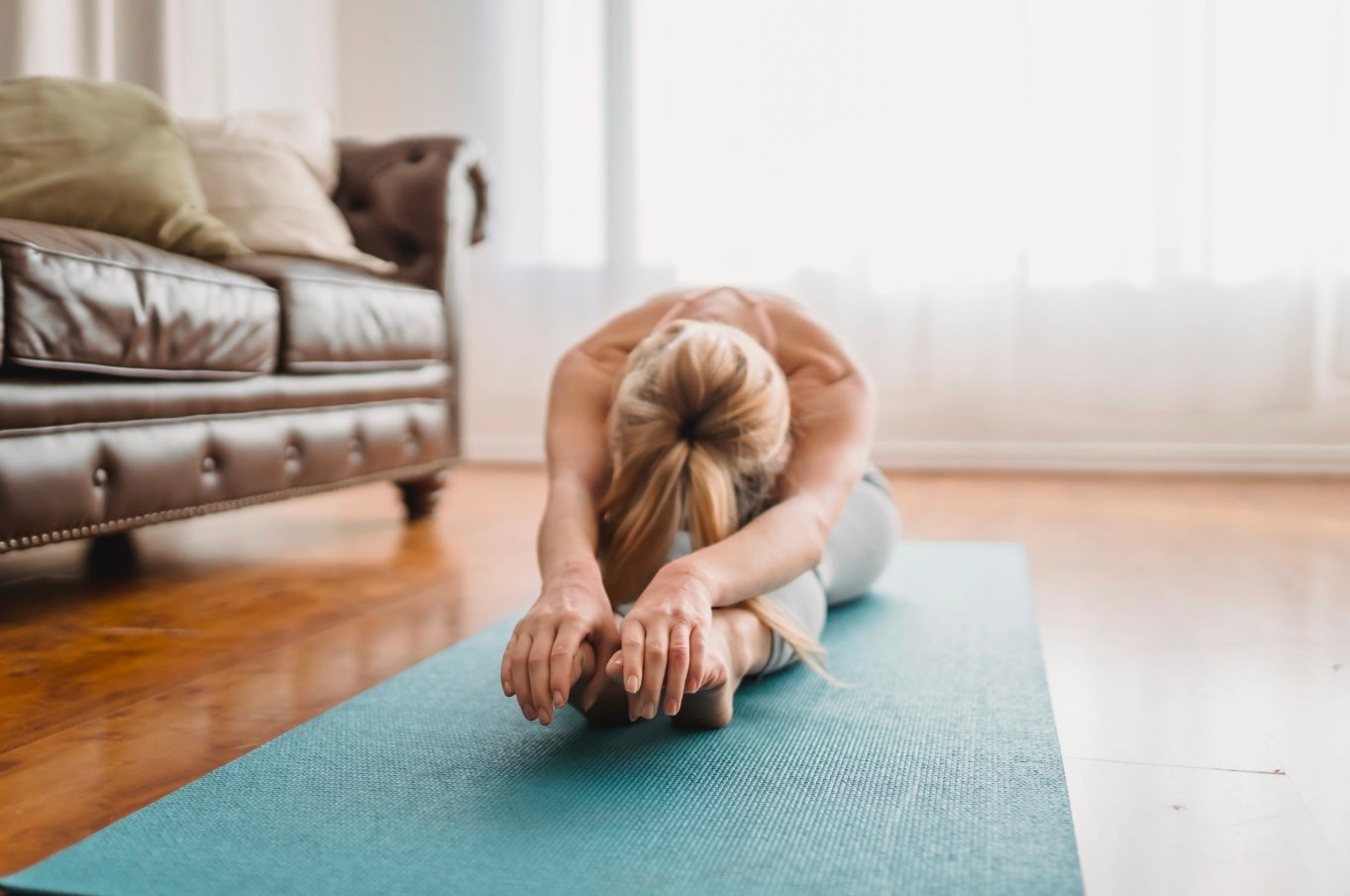 A woman engaged in yoga on a blue mat, showcasing her balance and concentration in a tranquil setting.