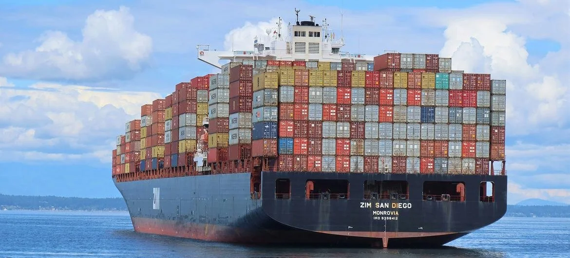 A large cargo ship with numerous stacked shipping containers sailing on water.