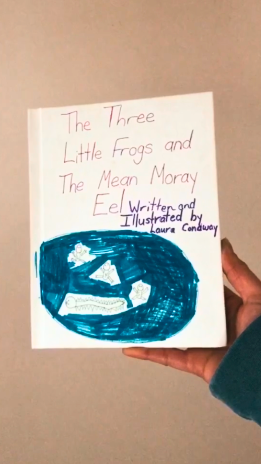 Author holding book cover of first published book in elementary school