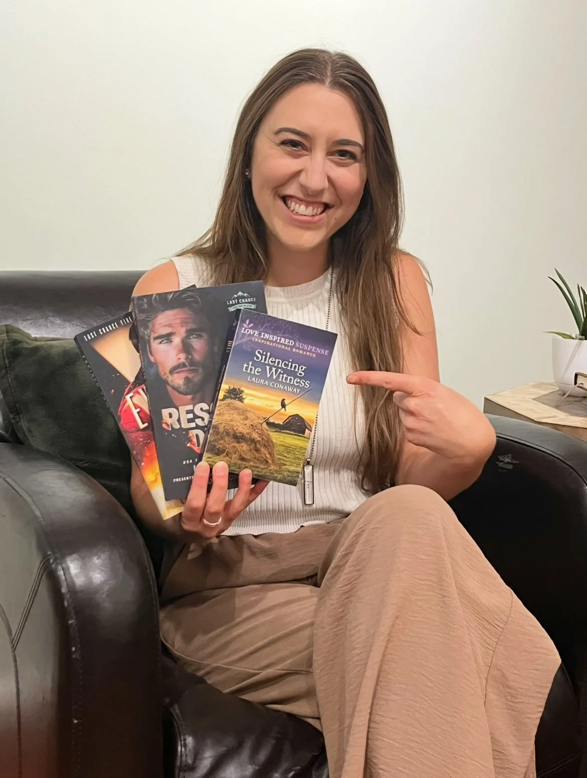 Author Laura Conaway holding three clean romantic suspense books set in small towns