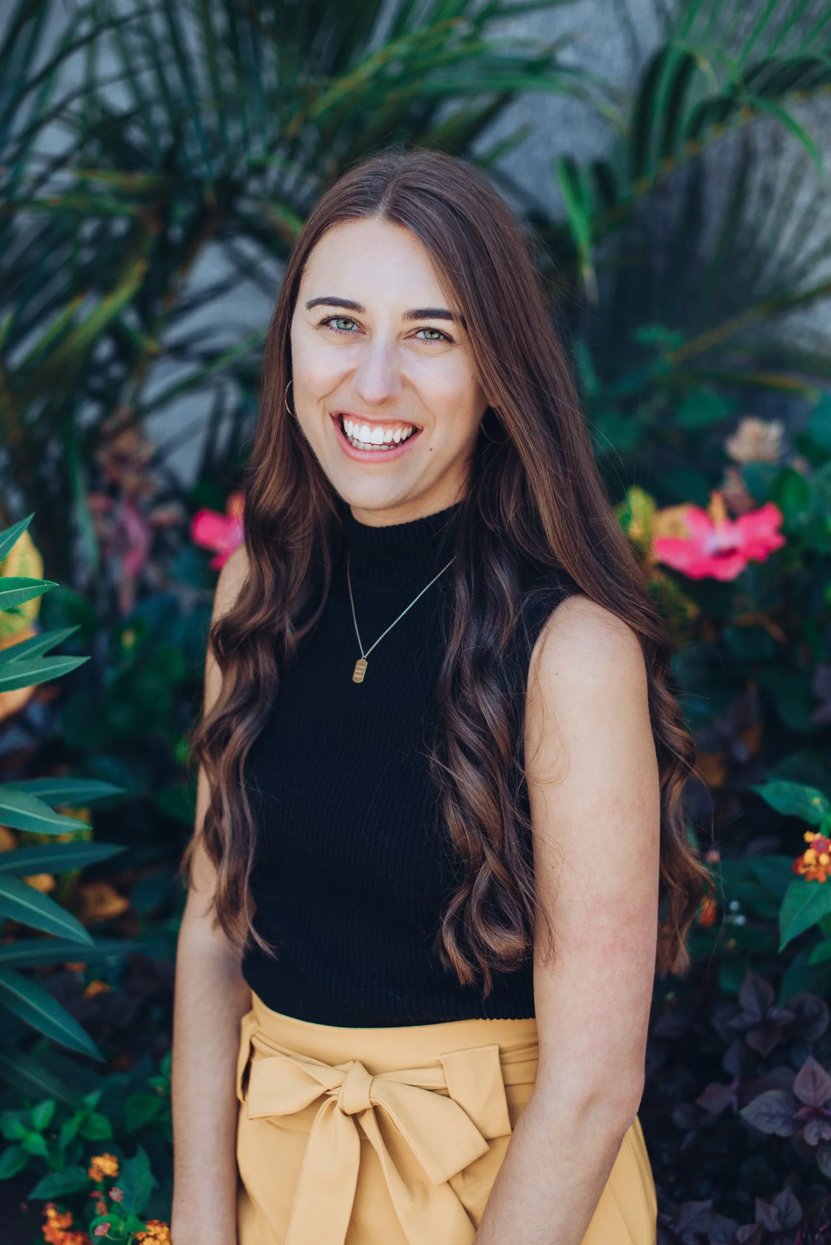 Laura Conaway standing in front of pink hibiscus flowers for an author headshot