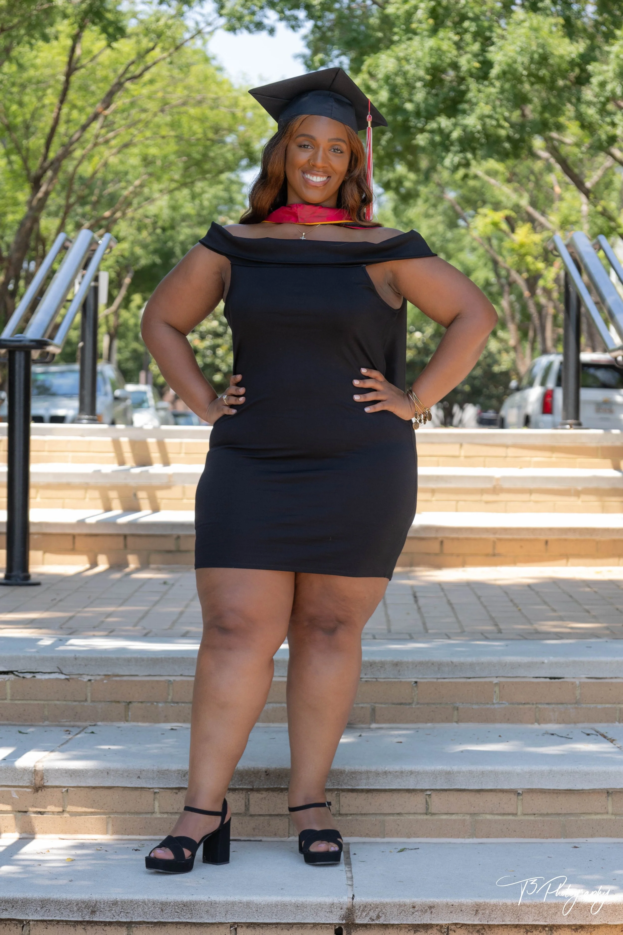 Graduate smiling in her cap and gown during an outdoor graduation portrait session.