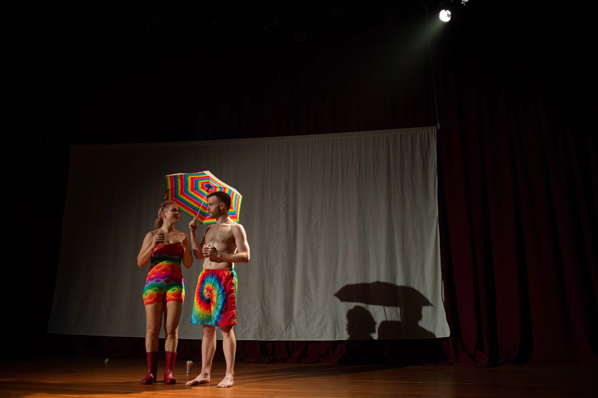 Lilli and Dylan dressed in rainbow bathing suits and a rainbow umbrella hold cans of la criox in a still from Good Grief!