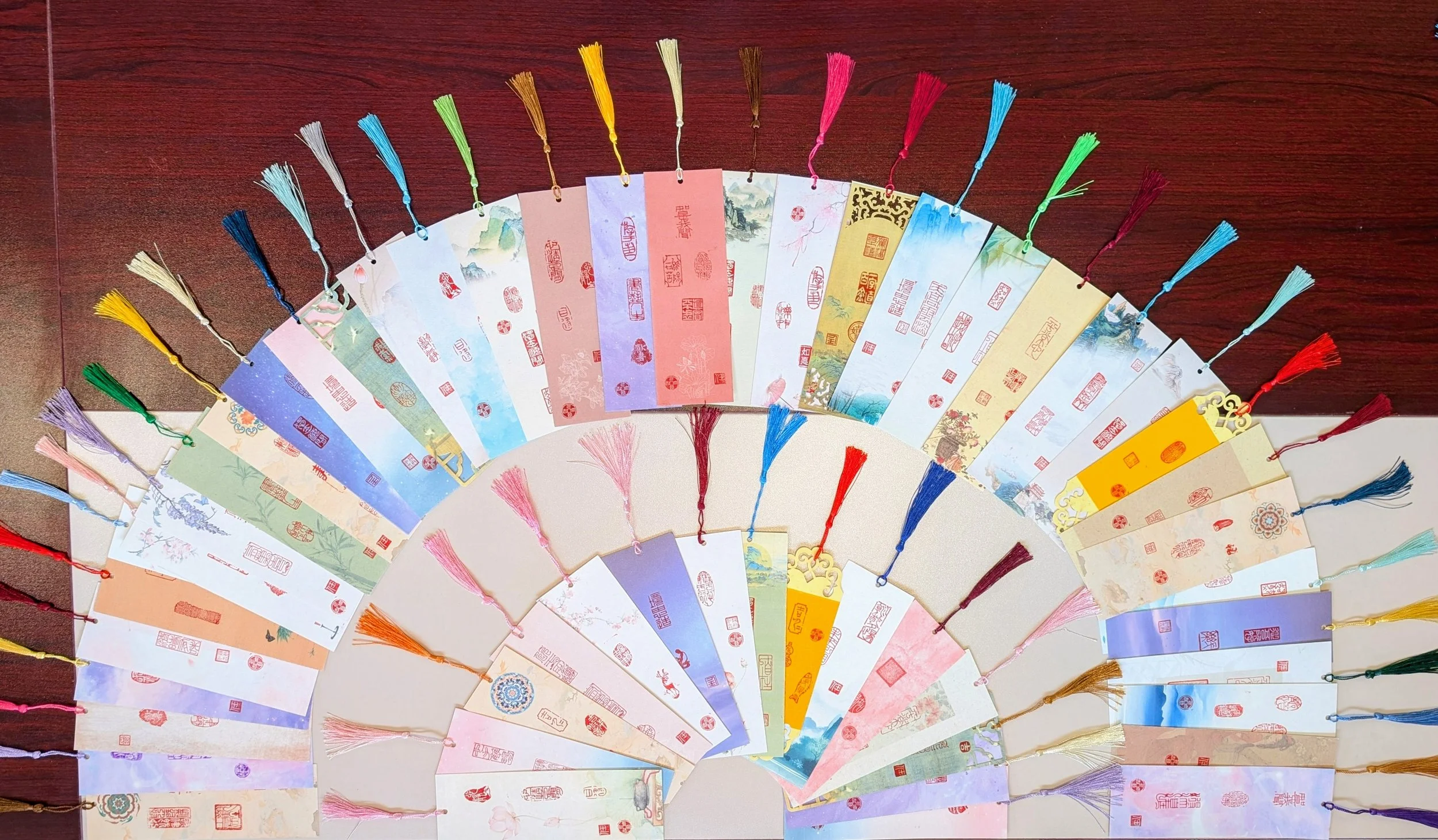 Accumulated XINYIN LIUNIAN bookmark works by Jingmin Ren, combining Chinese seal impressions, coloured paper and tassels.