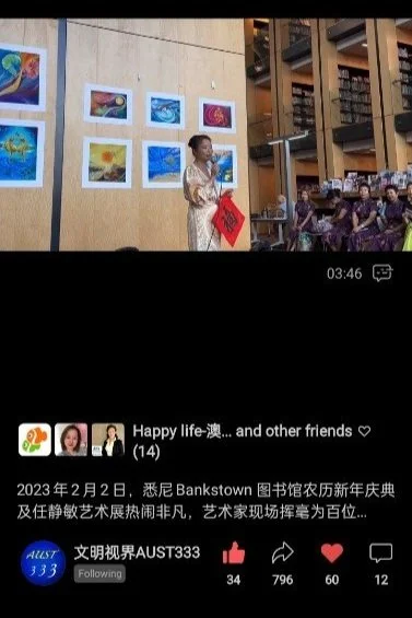 A woman standing in front of a display of colorful paintings at an indoor event, with an audience seated to the right.