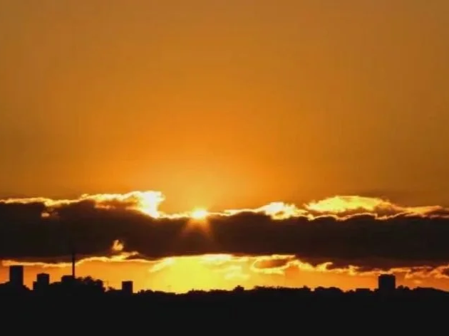 Sydney sunrise with golden light breaking through dark clouds above the city skyline, photographed by Jingmin Ren for the Sydney Morning series.