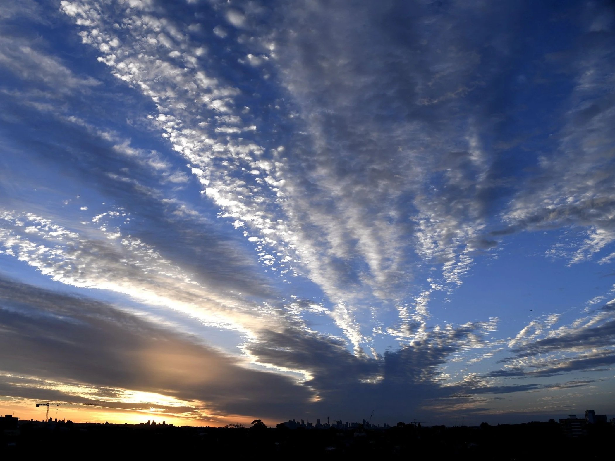 Radiating clouds and changing light over Sydney at sunrise, photographed by Jingmin Ren.