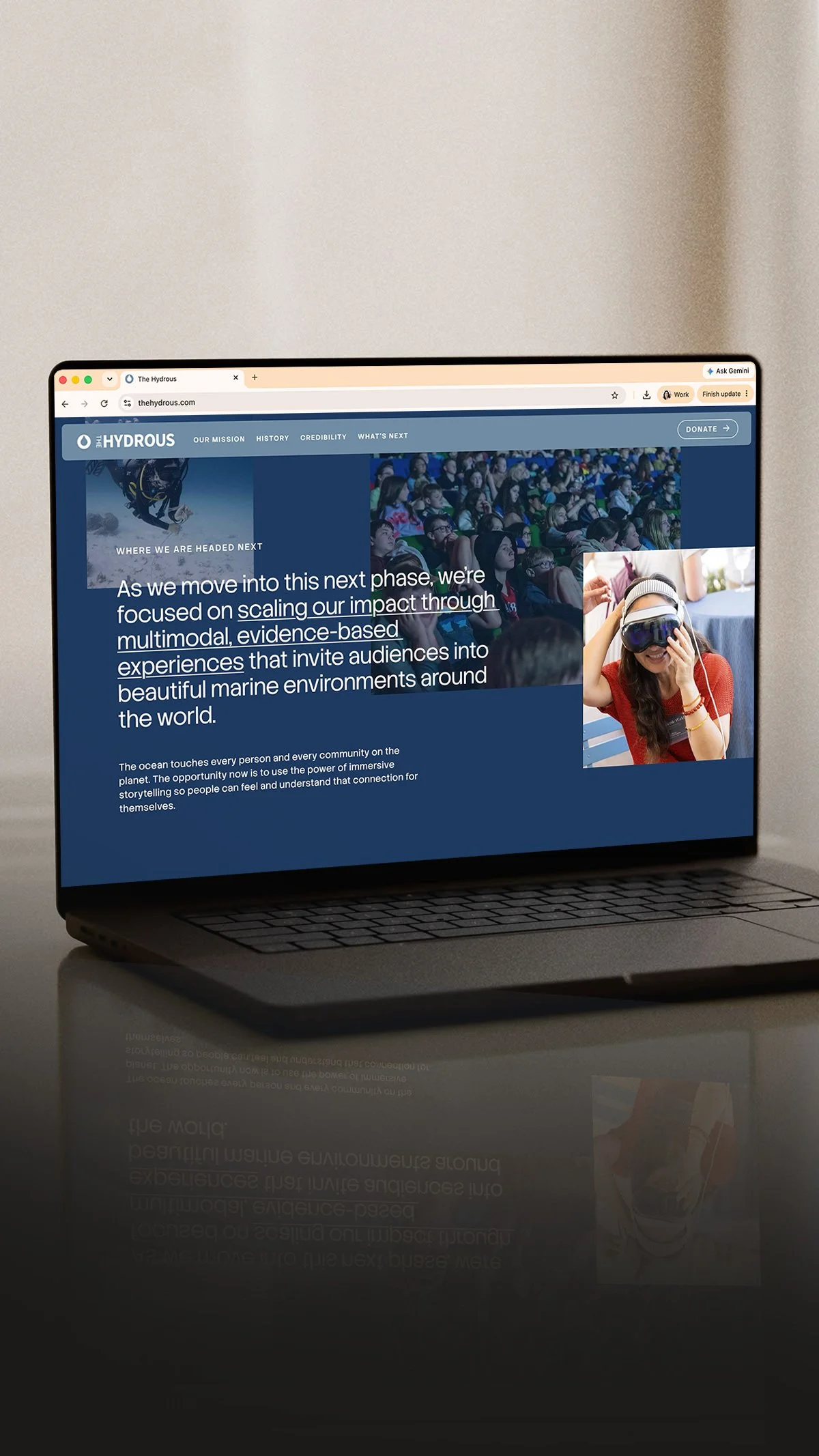 Laptop displaying a website about ocean conservation, with a photo of a woman in virtual reality and a scene of an audience in an auditorium.